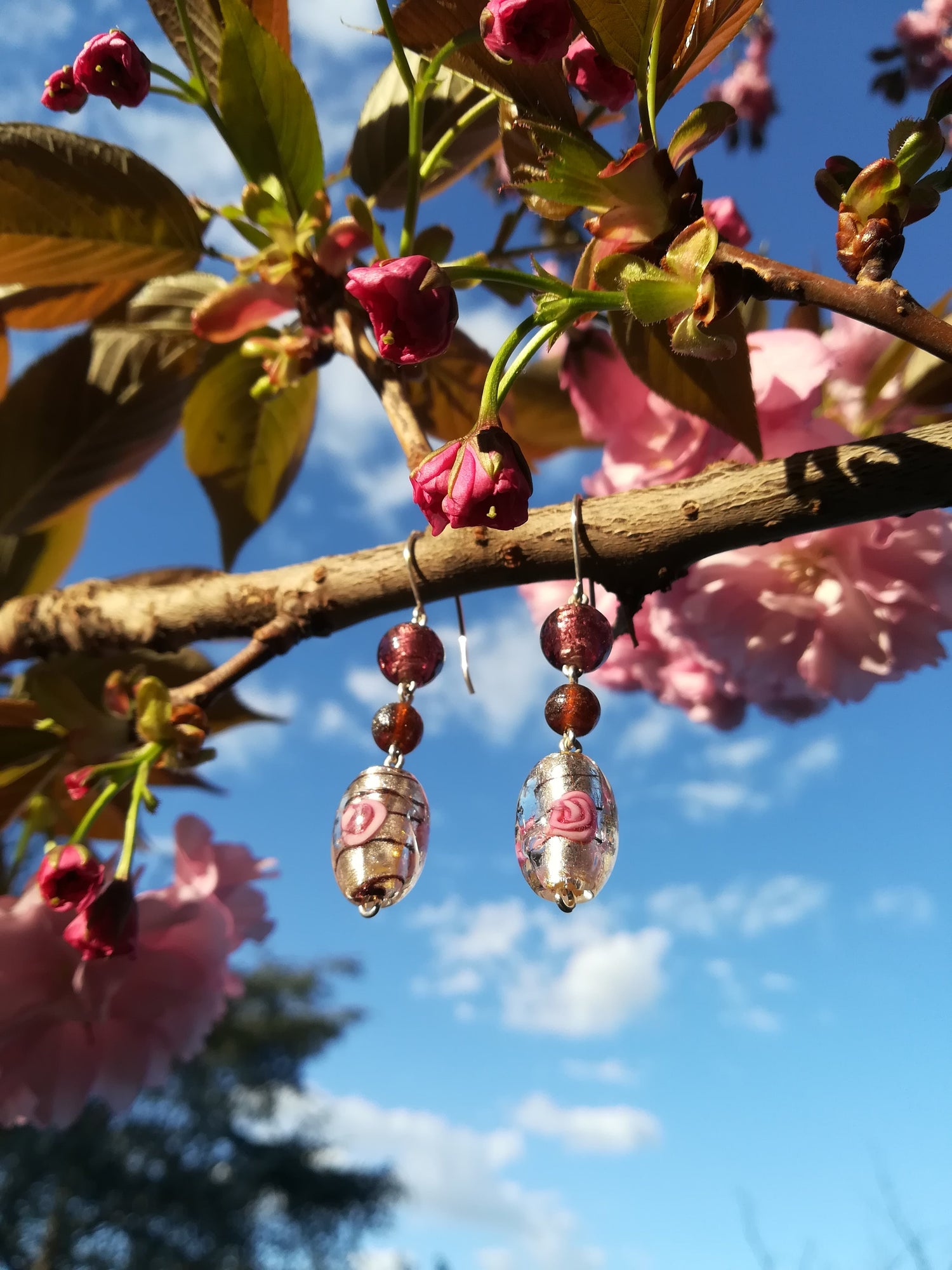 Orecchini femminili artigianali in vetro di murano e pietre naturali in contesto naturale.