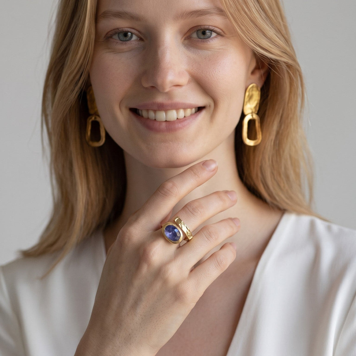Modella indossa anello DSCREAZIONI Frammento Zaffiro in bronzo dorato 18k con zaffiro ovale e orecchini coordinati